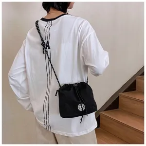 Vista posteriore di una borsa a secchiello in nylon nero con coulisse su un outfit casual.