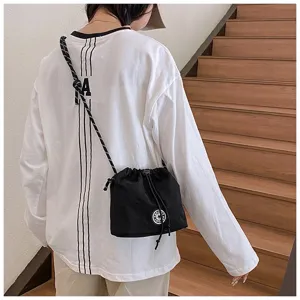 Vista posteriore di una borsa a secchiello in nylon nero con coulisse indossata da una modella