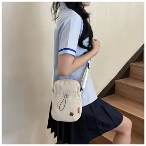 Lifestylefoto van een lichtgewicht beige nylon crossbody tasje voor meisjes in schoolstijl