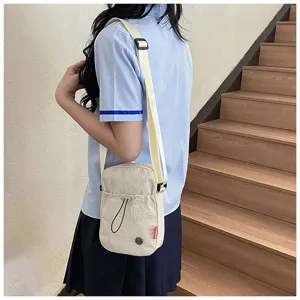 Minimalistische crème nylon kleine crossbodytas gedragen door een model in scène