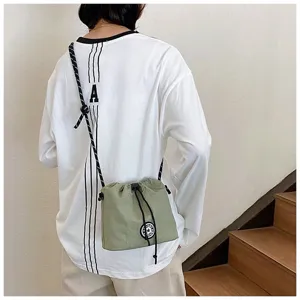 Dettaglio di borsa a tracolla in nylon verde oliva con coulisse su modella