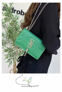 Detailopname van een trendy groene gewatteerde tas met gouden SS-logo en kettingriem