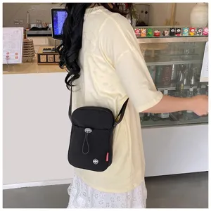 Detailopname van een meisje met een zwarte nylon crossbody tas in een caféomgeving