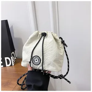 Dettaglio borsa a secchiello in nylon bianco con tracolla a corda nera e patch