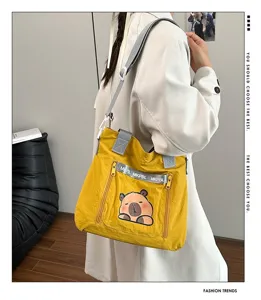 Detailed view of yellow canvas tote bag with cute capybara print and grey straps.