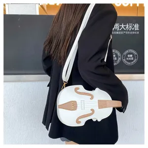 Close-up of white violin-shaped crossbody bag worn by a model in a black blazer