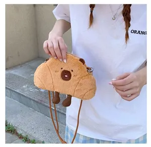 Detailed view of a cute brown plush capybara crossbody bag held by a person outdoors