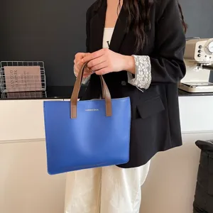 Primer plano de un bolso tote azul llevado por una mujer con atuendo de oficina