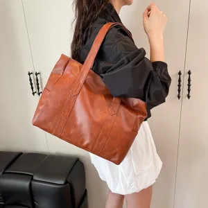 Bolso tote grande de cuero sintético vintage marrón llevado por una mujer en estilo casual