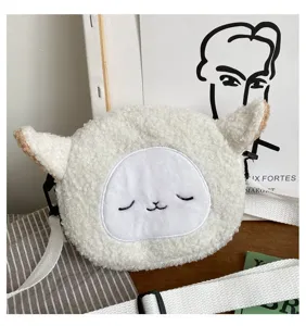 Vue détaillée d'un sac à bandoulière en peluche mouton blanc avec un visage brodé.