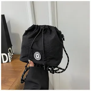 Dettaglio ravvicinato della borsa a secchiello in nylon nero con coulisse e patch SPORT.