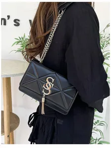 Detail van een stijlvolle zwarte gewatteerde crossbodytas met gouden ketting en kwast