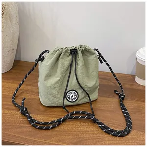 Dettaglio della borsa a secchiello in nylon verde salvia con tracolla in corda.