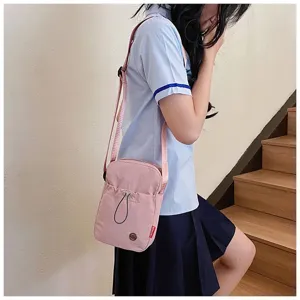 Modieuze roze nylon schoudertas voor studenten gedragen door model in schooluniformstijl