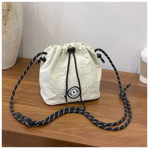 Dettaglio di una borsa a secchiello in nylon beige con chiusura a coulisse e corda.