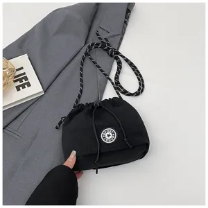 Primo piano di borsa a secchiello nera in nylon con toppa a stella su blazer grigio.