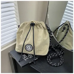 Primo piano di una borsa a secchiello in nylon beige con coulisse e patch sport