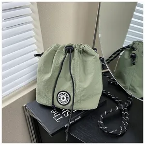 Vista dettagliata di una borsa a secchiello in nylon verde con coulisse e patch a stella