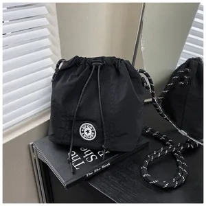 Dettaglio borsa a secchiello in nylon nero con coulisse e toppa a stella sportiva