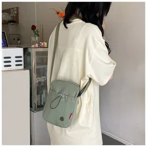 Achteraanzicht van een meisje met een lichtgroene nylon crossbodytas in een café