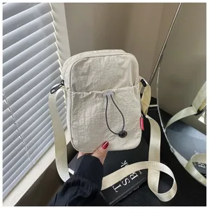 Detailweergave van de lichte crèmekleurige nylon schoudertas met trekkoordvak