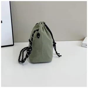 Vista laterale di una borsa a secchiello in nylon verde con tracolla in corda