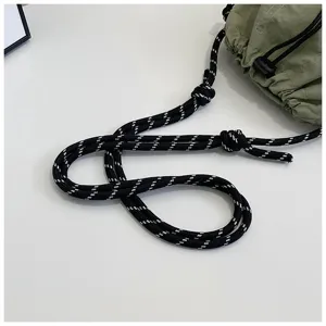 Dettaglio della robusta tracolla in corda intrecciata bianca e nera sulla borsa a secchiello