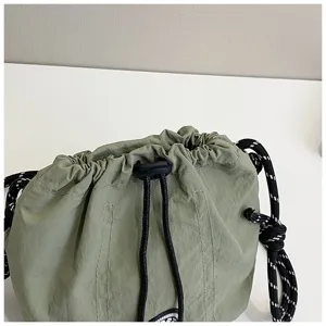Primo piano di una borsa a secchiello leggera in nylon verde oliva con coulisse e dettagli
