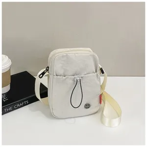 Gedetailleerde close-up van een minimalistische nylon crossbodytas in een roomwitte kleur