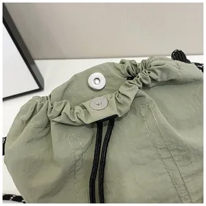 Dettaglio della borsa a secchiello in nylon con bottone magnetico e cordino nero