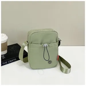 Gedetailleerd overzicht van een minimalistische lichtgroene nylon crossbodytas op tafel