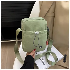 Detailweergave van een lichte groene nylon crossbody tas met een voorzak met trekkoord