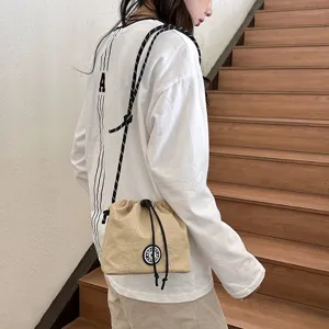 Piccola borsa a tracolla beige in nylon con coulisse indossata in un ambiente interno