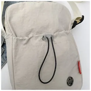 Detailopname van het trekkoord van een minimalistische beige nylon telefoontasje