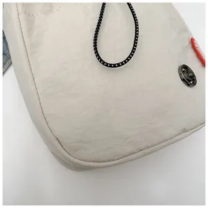 Detailopname van een nylon schoudertas met focus op de textuur en het ronde logo