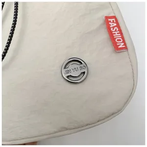 Gedetailleerd overzicht van gebroken witte nylon schoudertas met zilveren logo en rood label.