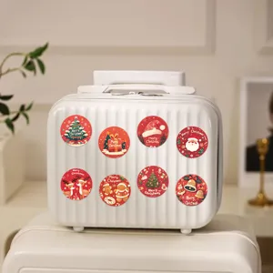Detailweergave van feestelijke rode kerststickers op een witte getextureerde koffer