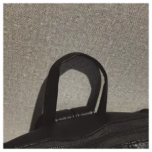 Nahaufnahme des Tragegriffs und Reißverschlusses eines schwarzen Rucksacks aus weichem Leder.