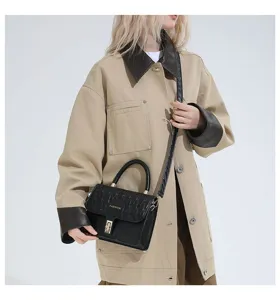 Detalle de un bolso bandolera bordado en negro sobre un modelo de gabardina beige