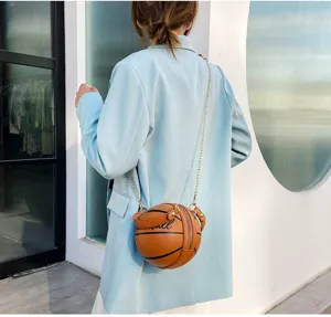 Detalle de un bolso bandolera único con forma de baloncesto marrón y cadena dorada