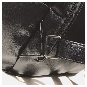 Makrodetail der schwarzen Weichledertextur und Silberschnalle an einem Damenrucksack