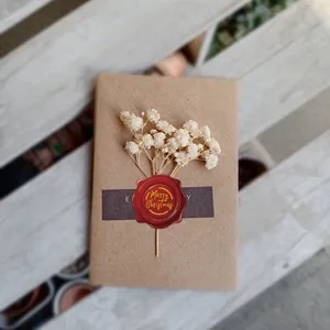 Close-up van rode Merry Christmas lakzegel sticker op kraft envelop met gedroogde bloemen