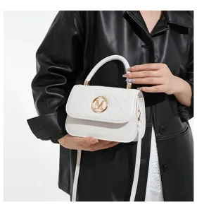 Nahaufnahme einer eleganten weißen gesteppten Umhängetasche mit goldenem M-Logo
