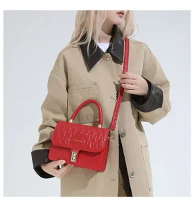 Elegante bolso bandolera rojo bordado mostrado en modelo con gabardina beige.