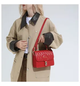 Bolso bandolera rectangular acolchado rojo llevado por una modelo con chaqueta beige chic.