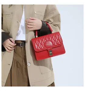 Detalle de una modelo sosteniendo un bolso de mano cuadrado rojo bordado con cierre dorado