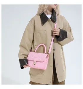 Vista detallada del bolso bordado rosa combinado con una chaqueta beige de moda.