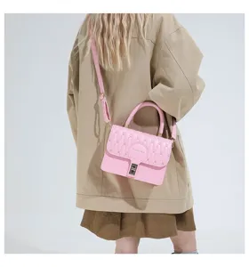 Primer plano de un bolso rosa bordado llevado sobre una elegante gabardina color beige