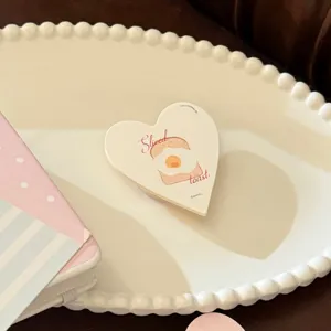 Support de téléphone en cœur avec illustration de toast sur un plateau décoratif blanc