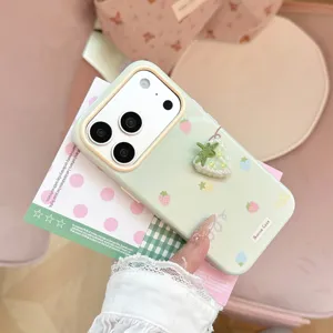 Détail d'une coque iPhone vert clair avec une breloque fraise en tissu 3D et des imprimés